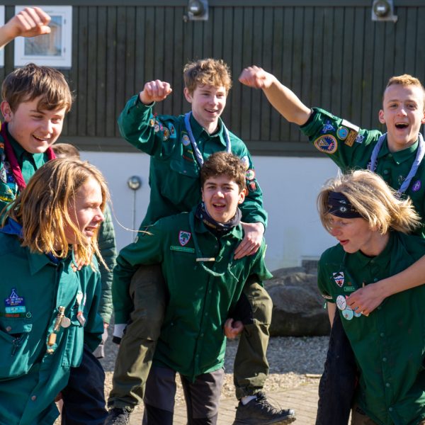 To spejderledere viser en færdselstavle for en gruppe børn