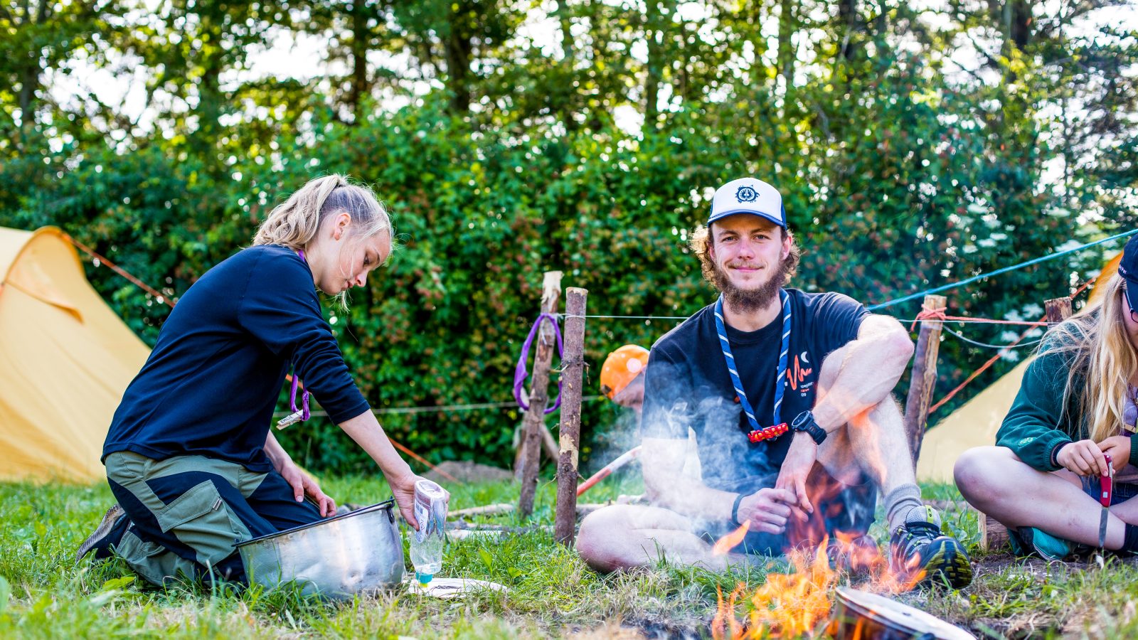 Spejdere på lejr, der sæber gryder ind ved bålet