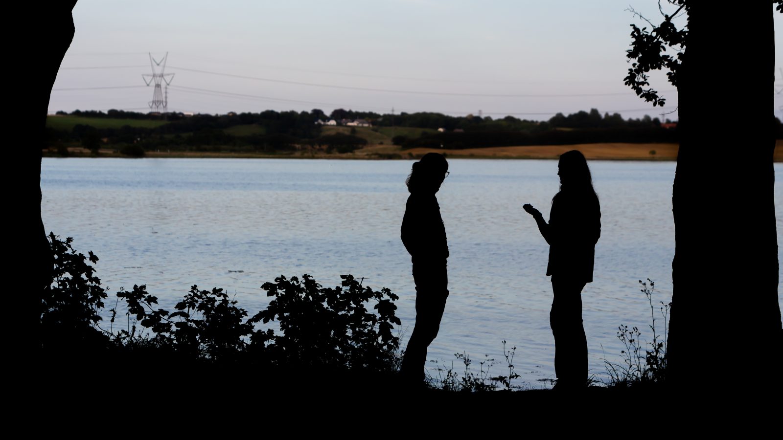 To mennesker taler sammen ved vandet til en korpsweekend