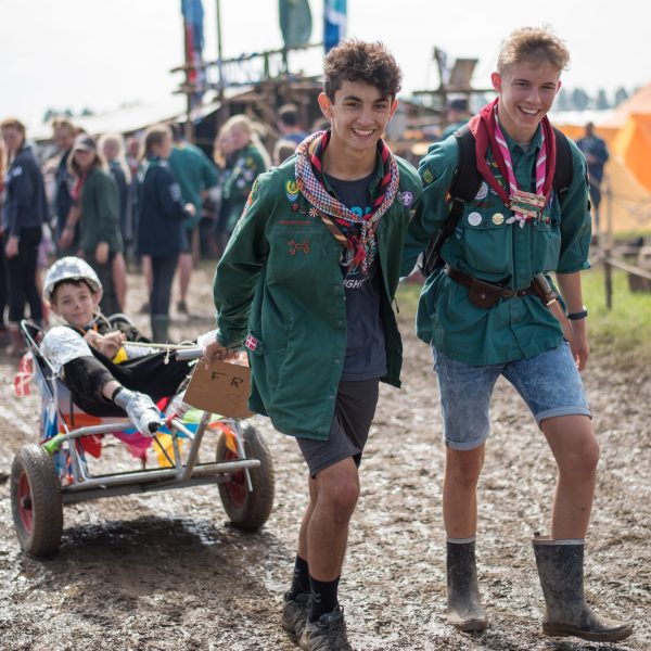 To spejderledere viser en færdselstavle for en gruppe børn