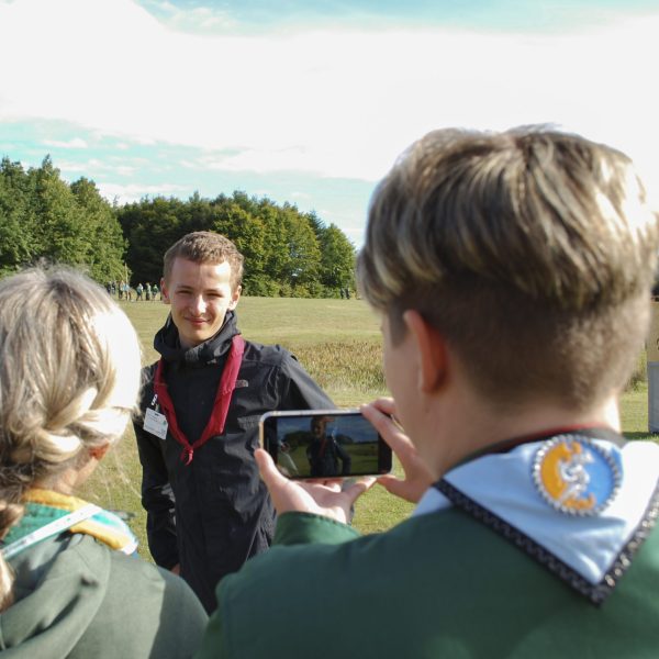 To spejderledere viser en færdselstavle for en gruppe børn