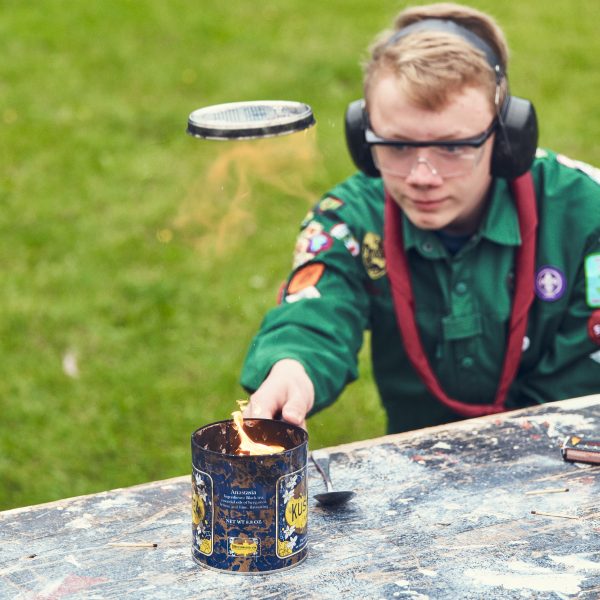 To spejderledere viser en færdselstavle for en gruppe børn